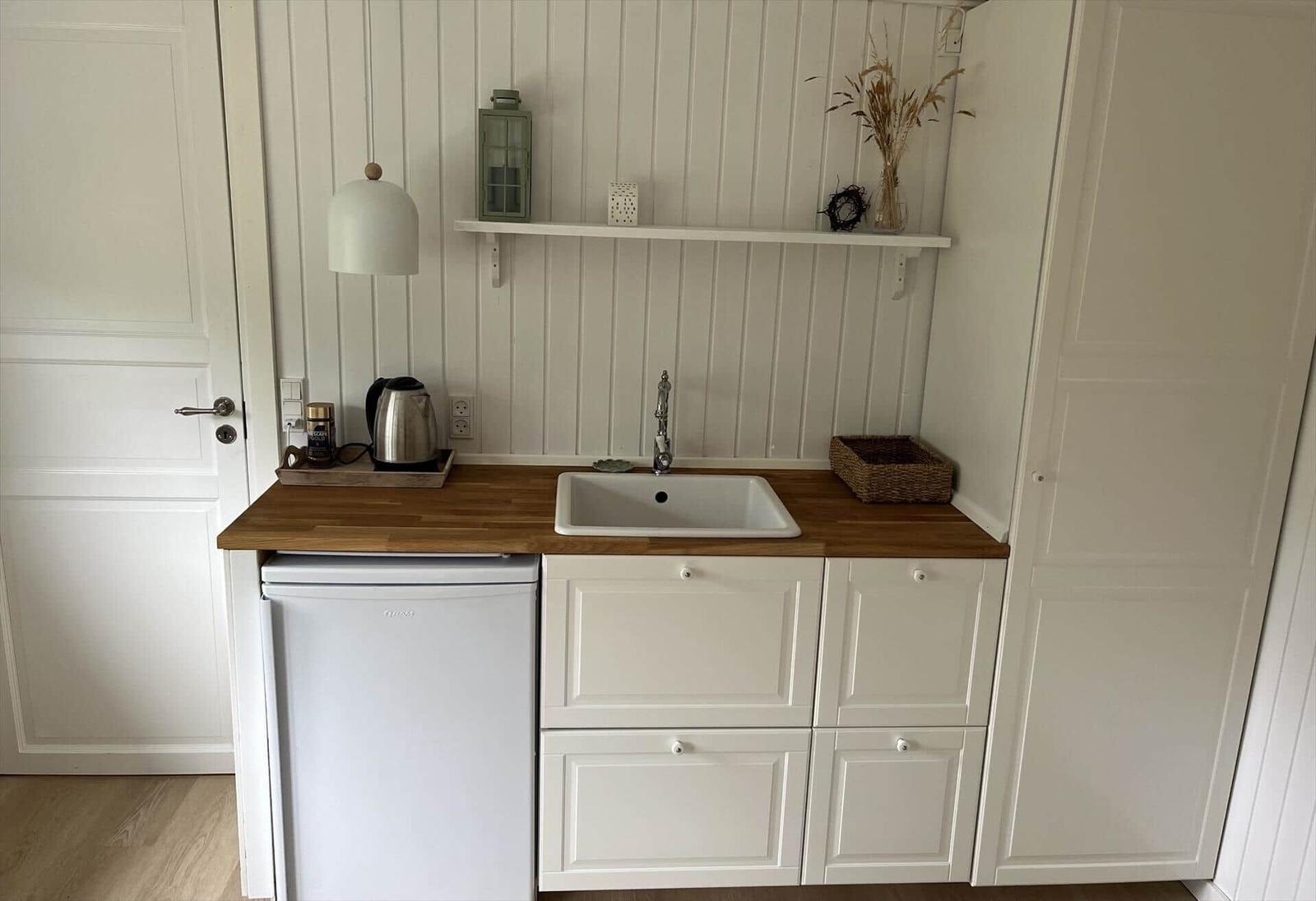 Küche mit Holzplatte, Spüle, Kühlschrank und Schrank