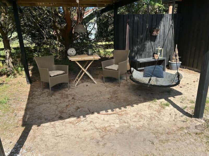 Terrasse mit Sitzgruppe, Tisch und Schaukel unter Dach