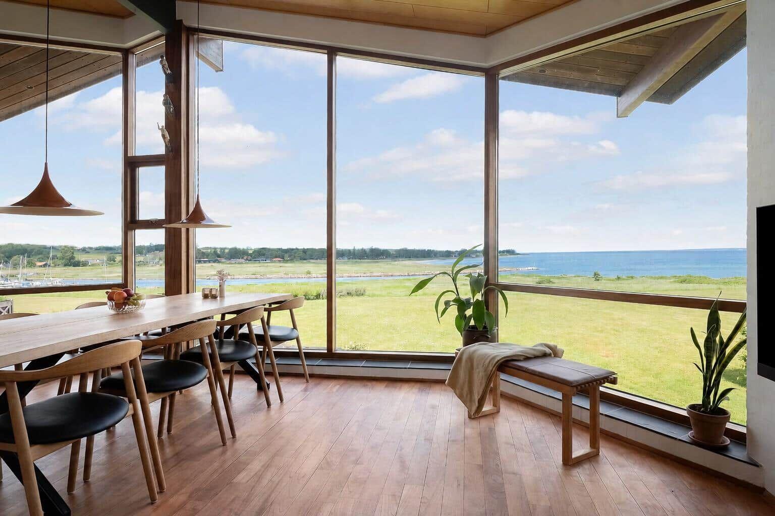 Dining room with large window view of sea and green land.