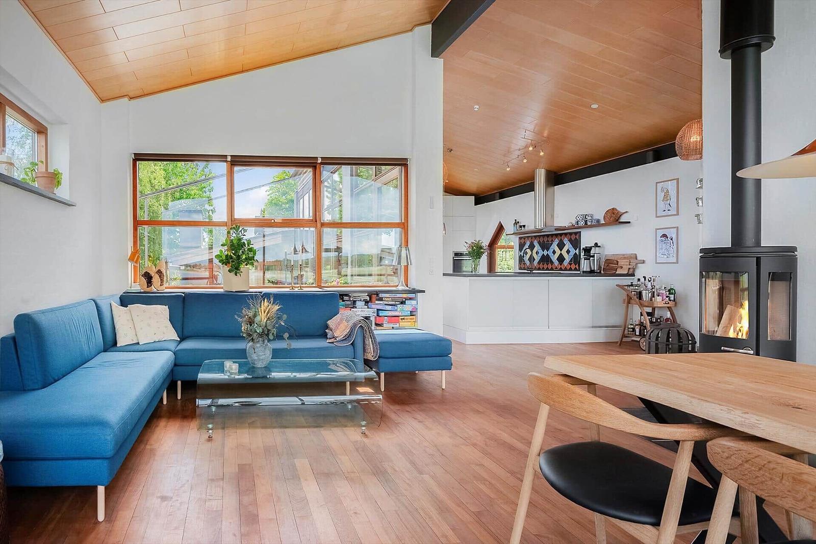 Living and dining area with hardwood floor, blue sofa, and wood-burning stove.