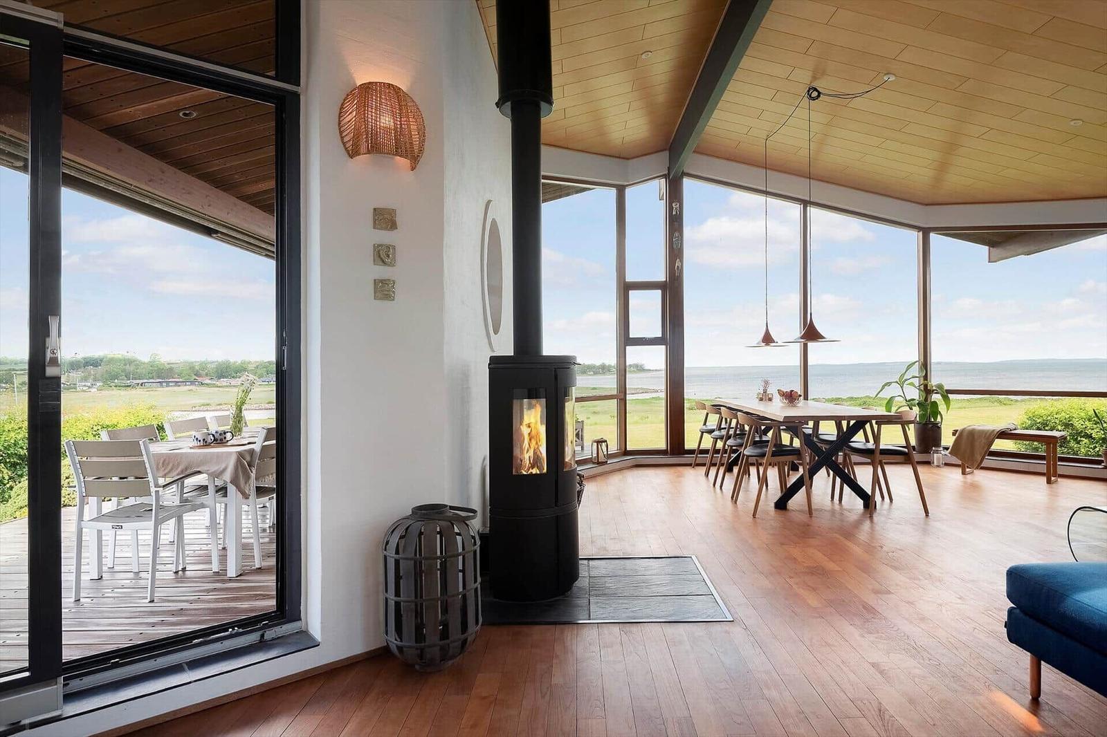 Room with wooden floor, fireplace, and large window view of water and green.