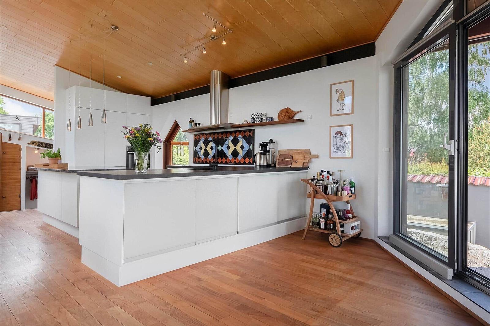 Kitchen with white countertop, wooden floor, and large windows.