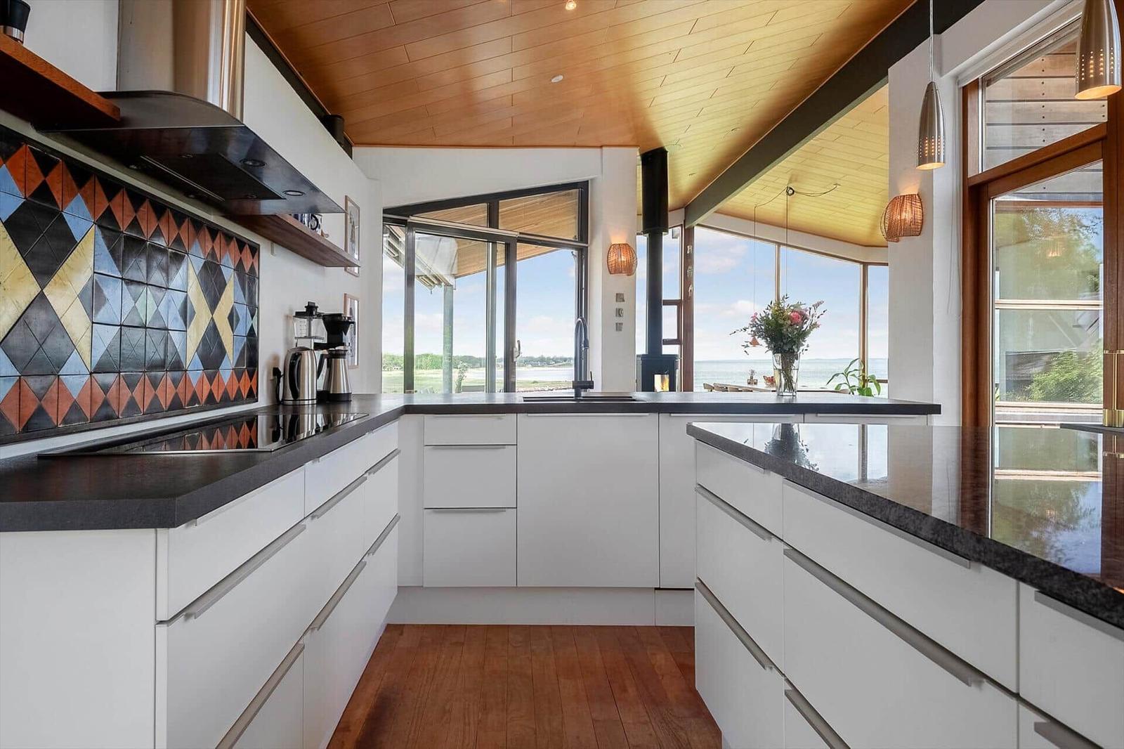 Modern kitchen with white cabinets and view of the sea
