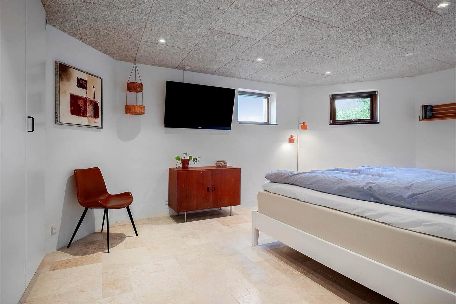 Bedroom with bed, TV, cabinet, and chair.