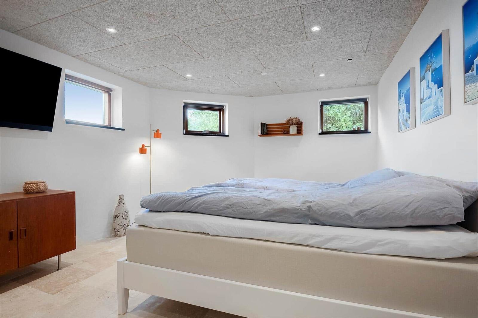 Bedroom with bed, windows, wall art, and TV.