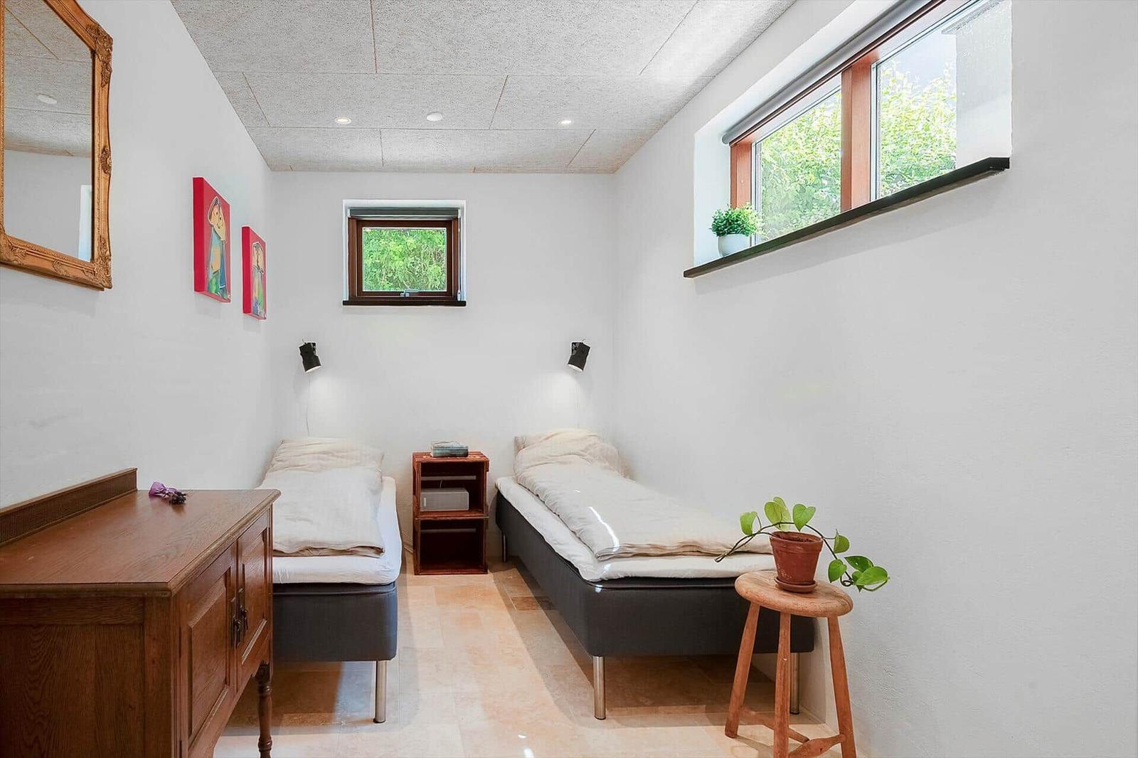Two single beds, windows, mirror, and plants in the bedroom.