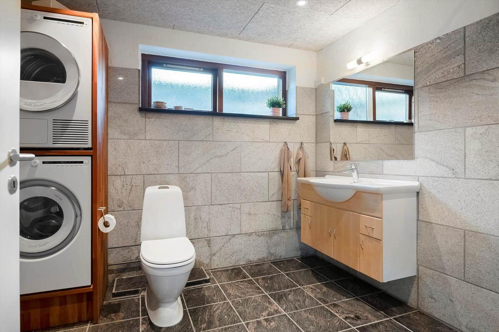 Bathroom with washing machine, dryer, toilet, and mirror