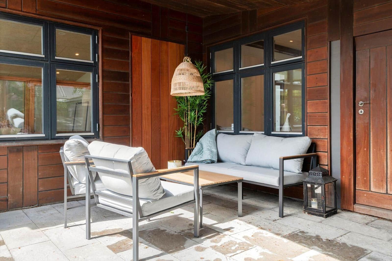 Terrace with seating group, table, and hanging lamp against wooden wall