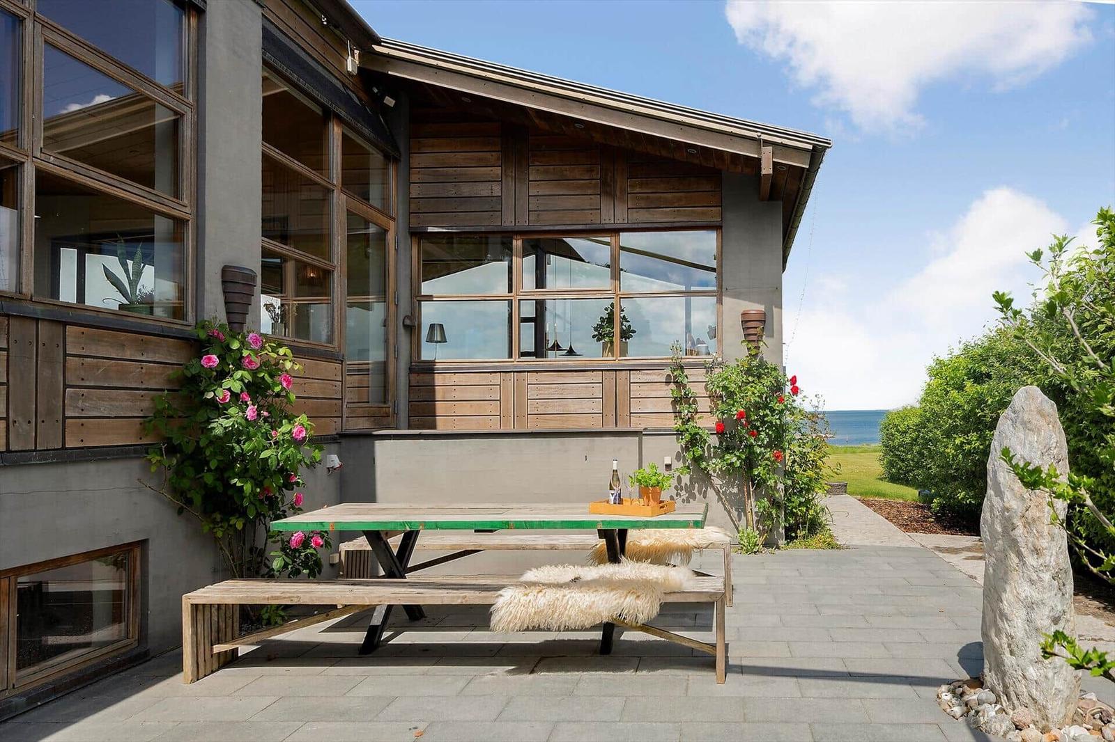 Terrace with wooden table, fur cushions, and sea view