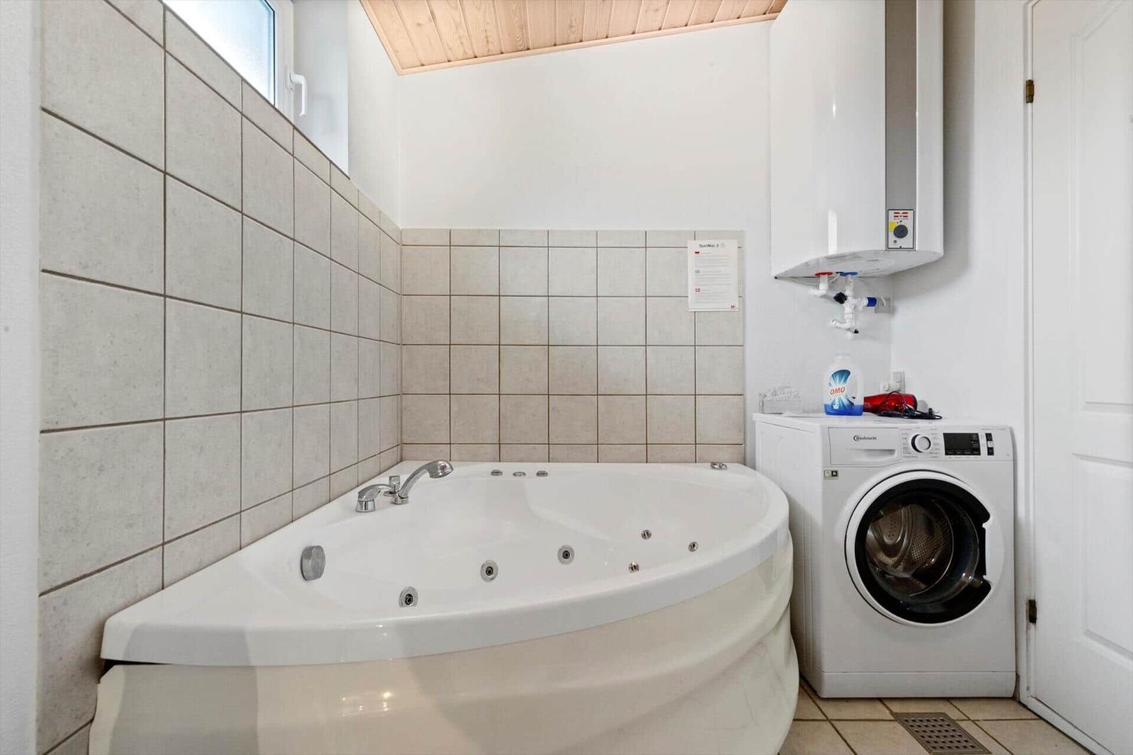 Bath with whirlpool, washing machine, and water heater on the wall.