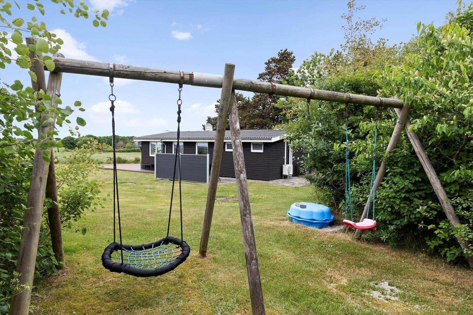 Backyard with playground equipment and small house in background.