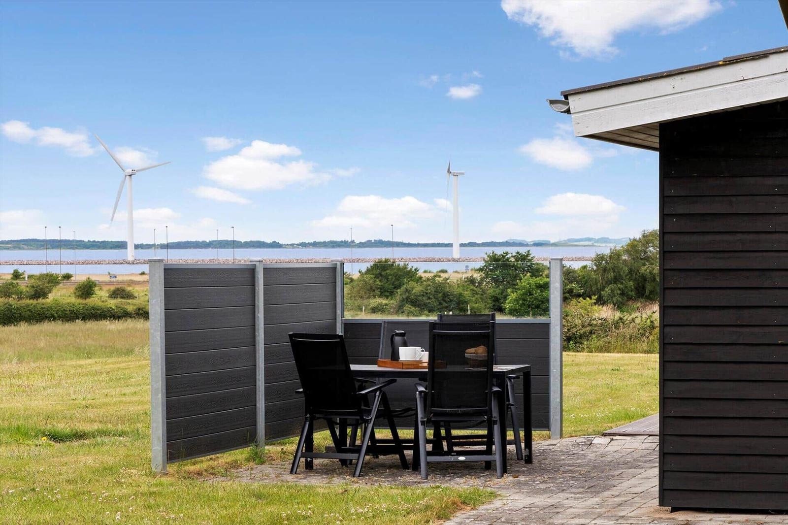 Terrace with table and chairs. View of wind turbines and water.