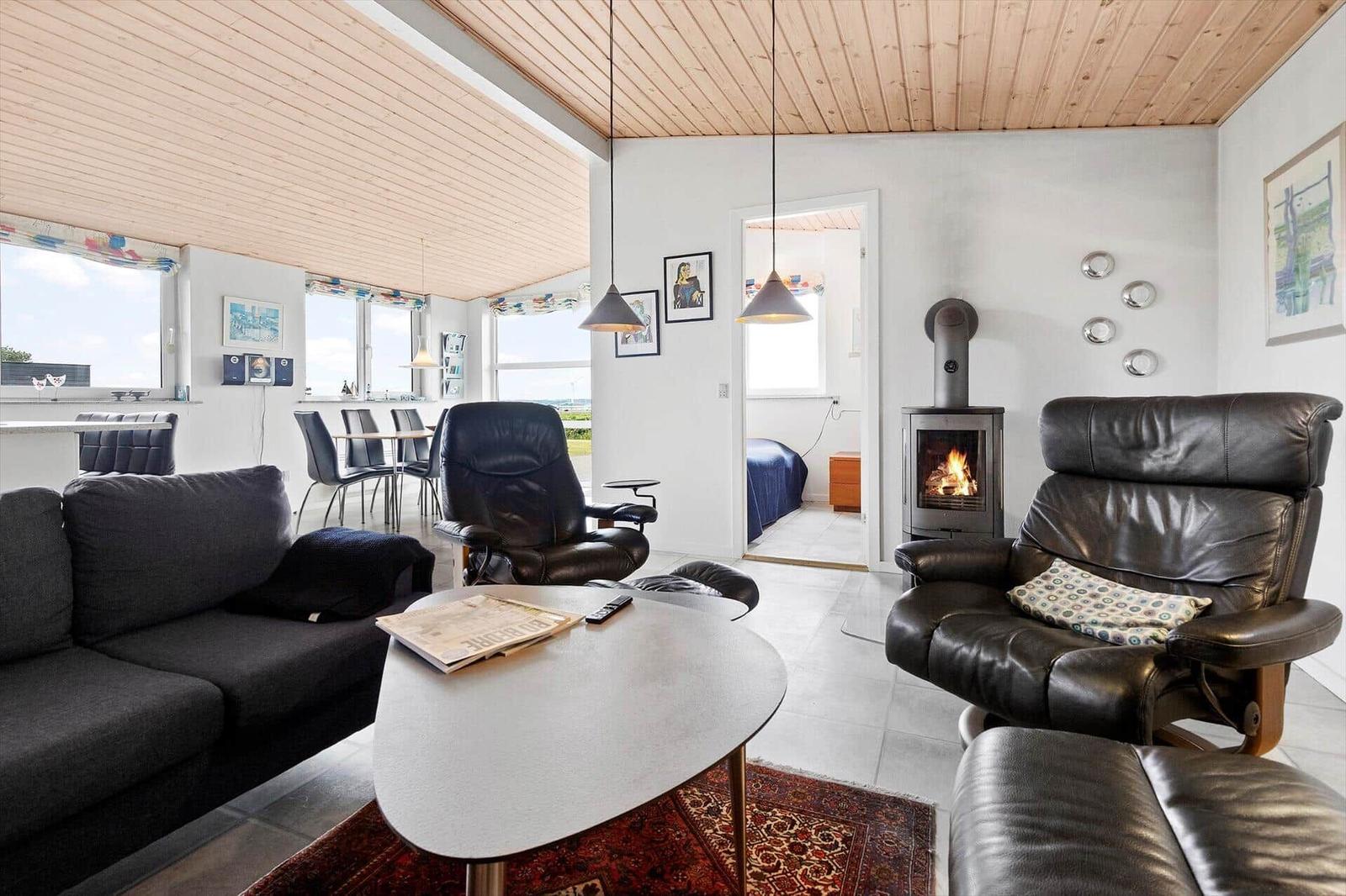 Living room with sofa, two leather chairs, and fireplace. Corridor to bedroom.