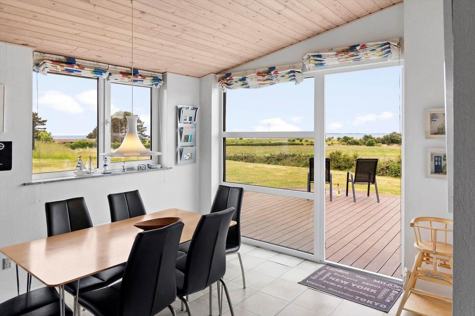 Dining area with table, chairs, and view of terrace and landscape.