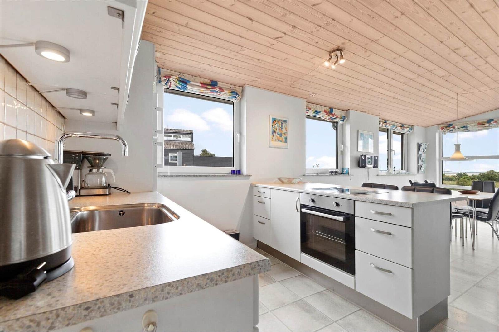Kitchen with worktop, stove, and windows with view.
