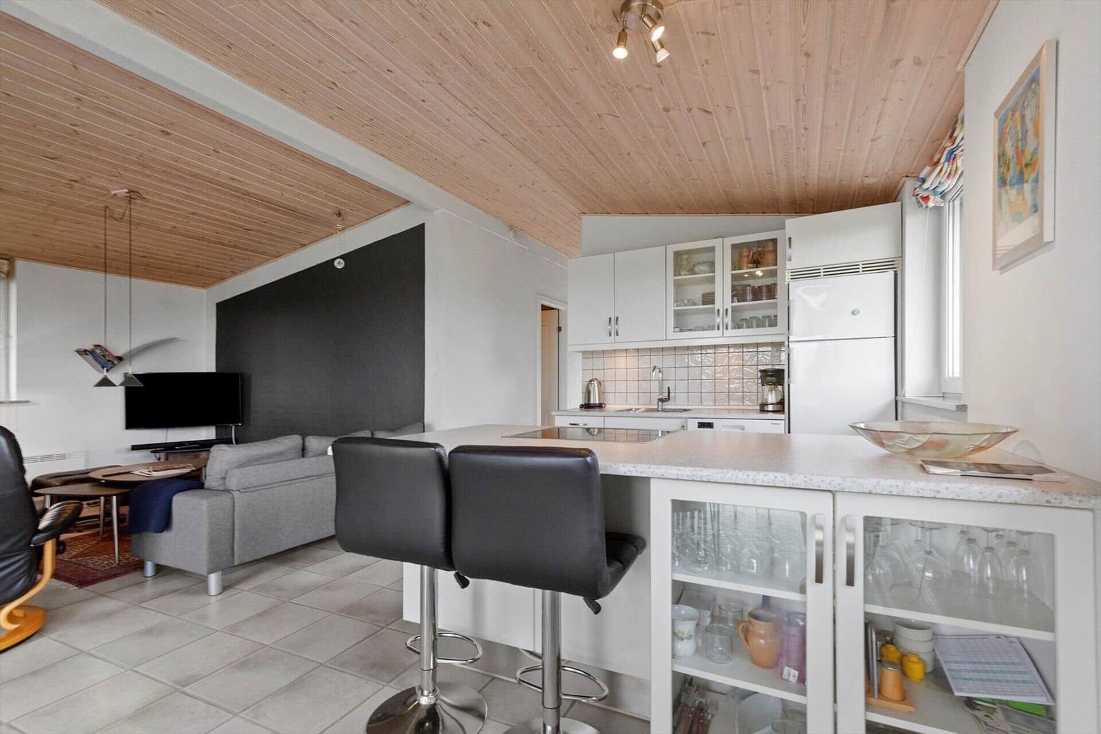 Kitchen with dining area and living room with sofa and TV.