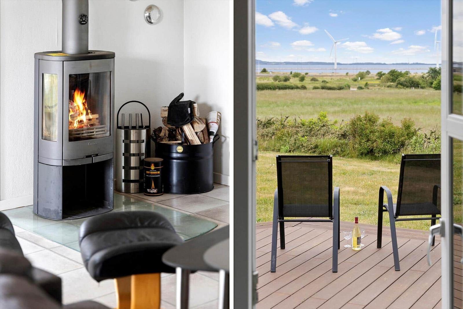 Indoor space with fireplace and outdoor terrace with seating and view of field and wind turbines.