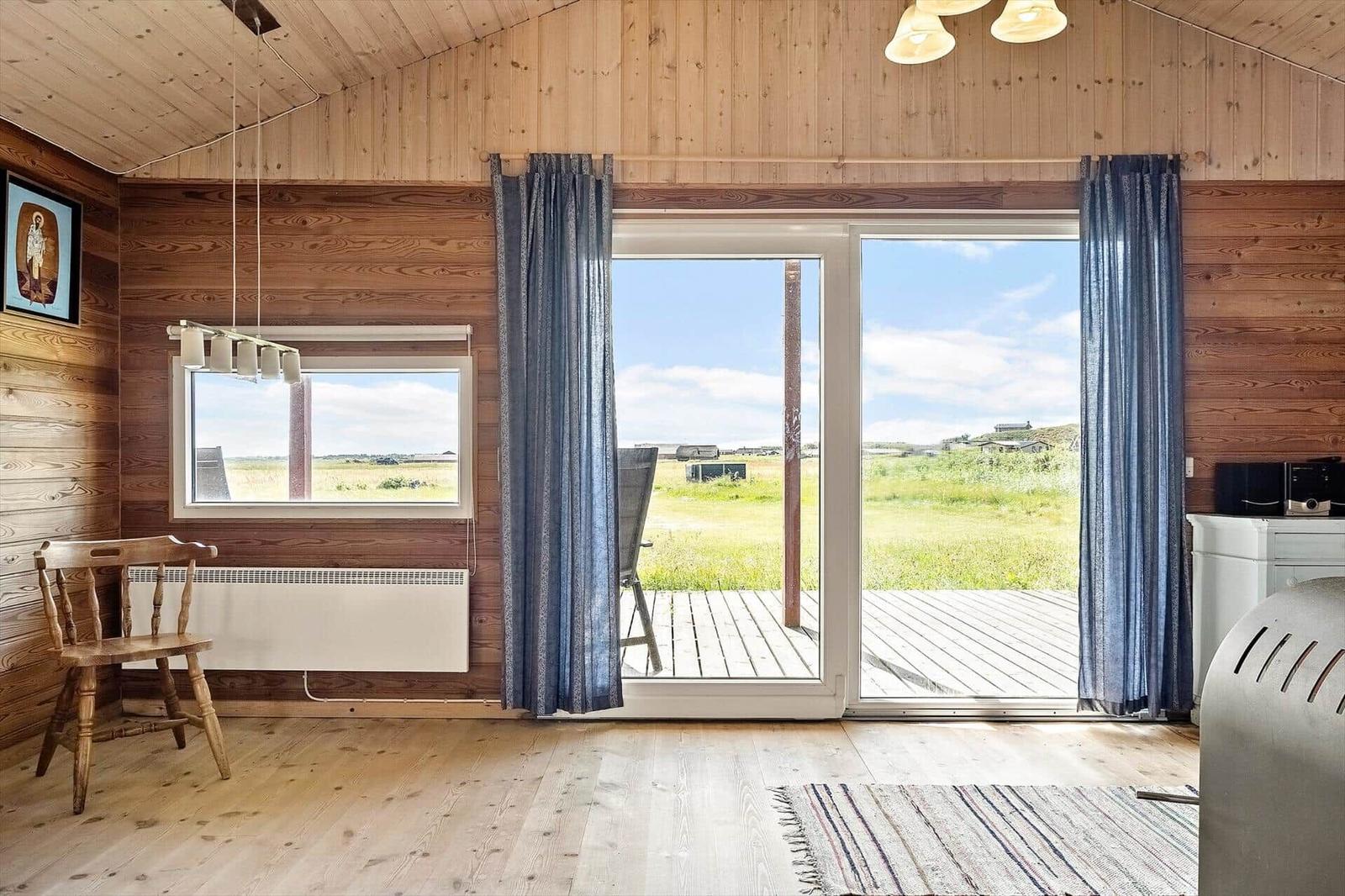 Holzvertäfelte Wohnung mit Blick auf grünes Feld und Terrasse
