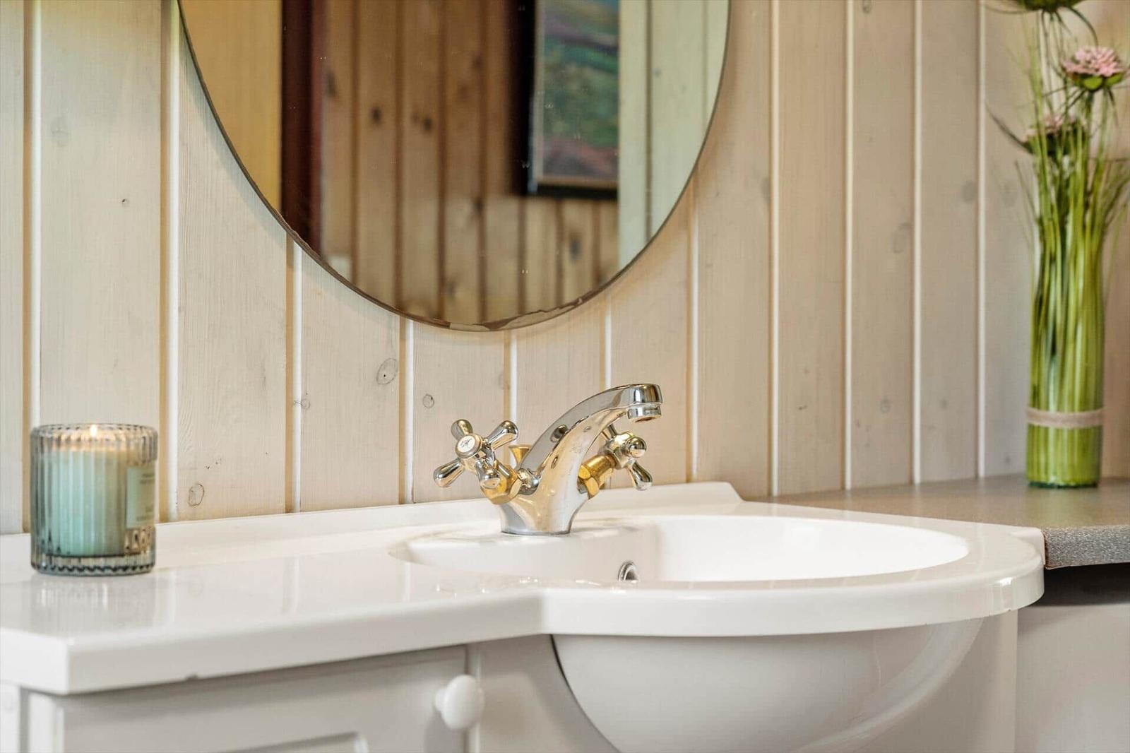 Waschbecken mit Spiegel und Kerze auf Holzwand