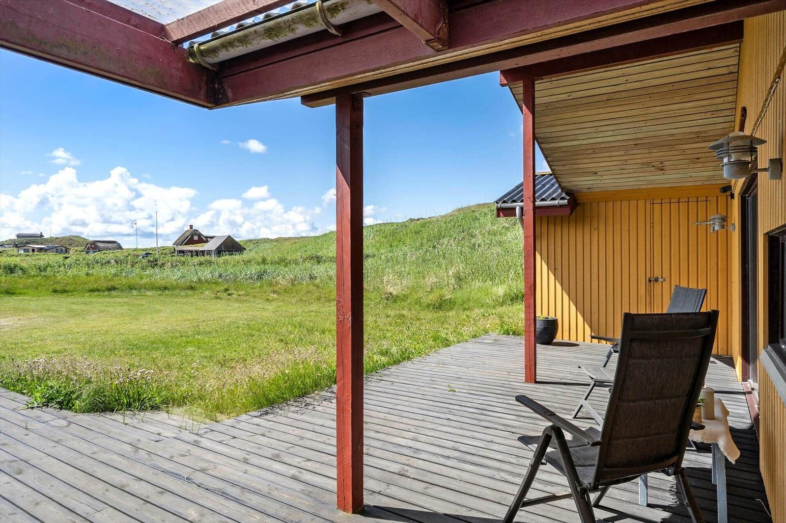 Terrasse mit Sitzgelegenheiten und Blick auf grüne Wiesen und Häuser im Hintergrund.
