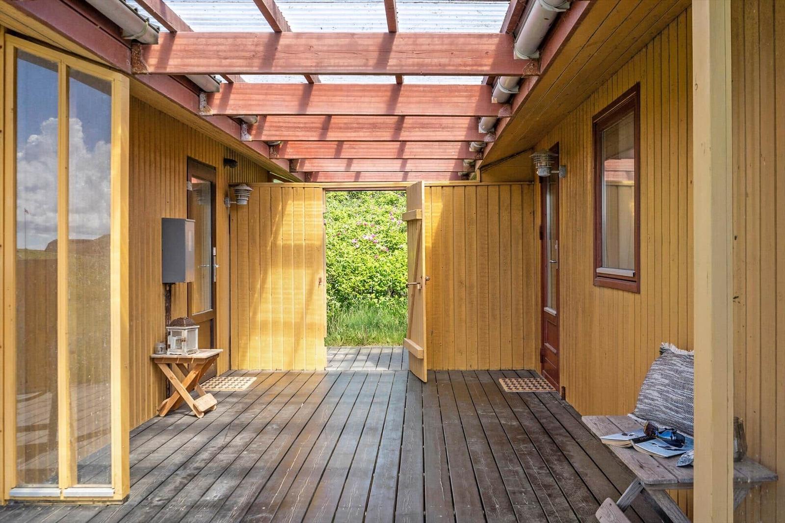 Holzveranda mit Dachkonstruktion und Blick auf grüne Landschaft.