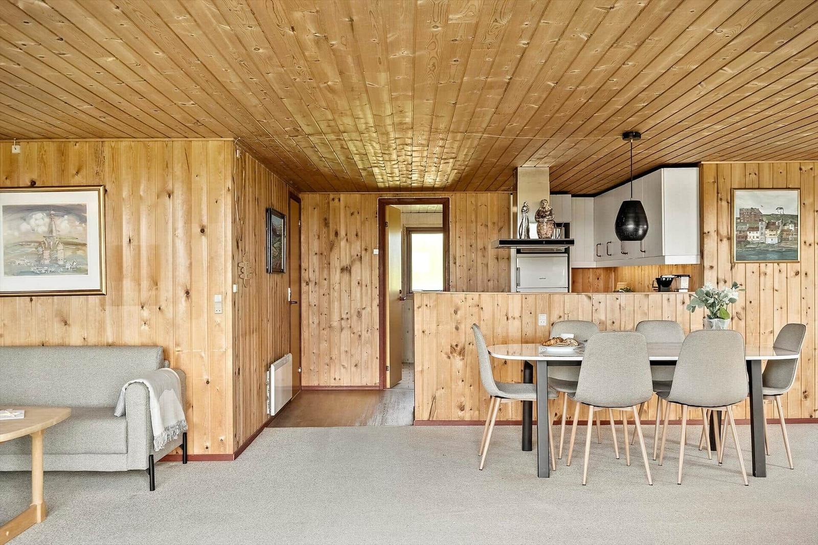 Wohn- und Essbereich mit Holzwandverkleidung und moderner Einrichtung.