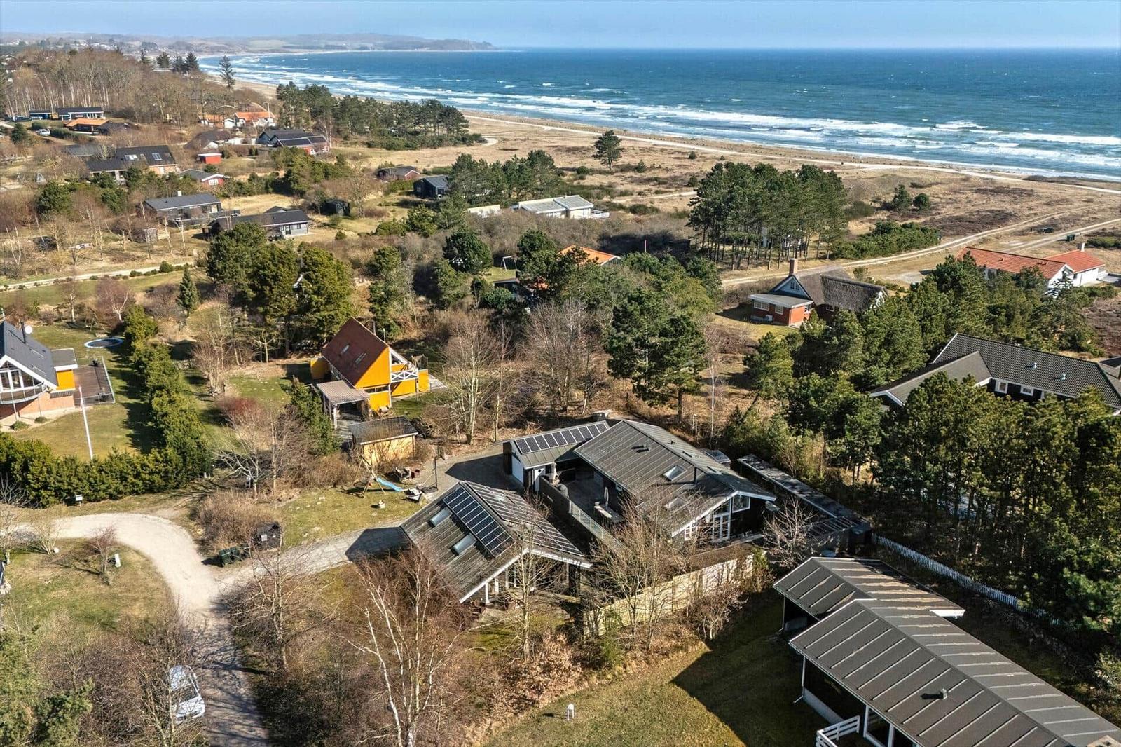 Haus mit Solaranlagen, umgeben von Wald und Strand