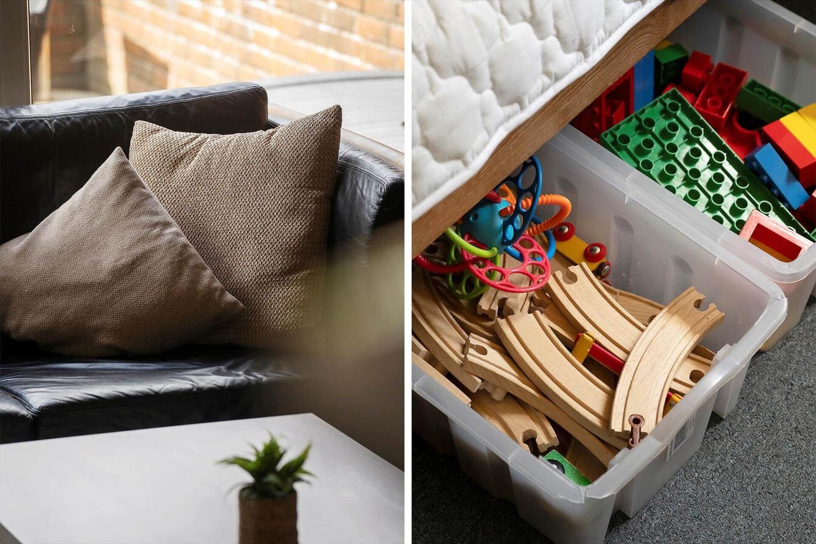 Schwarzes Sofa mit Kissen und Pflanze. Spielzeugboxen mit Bahn und Bausteinen.
