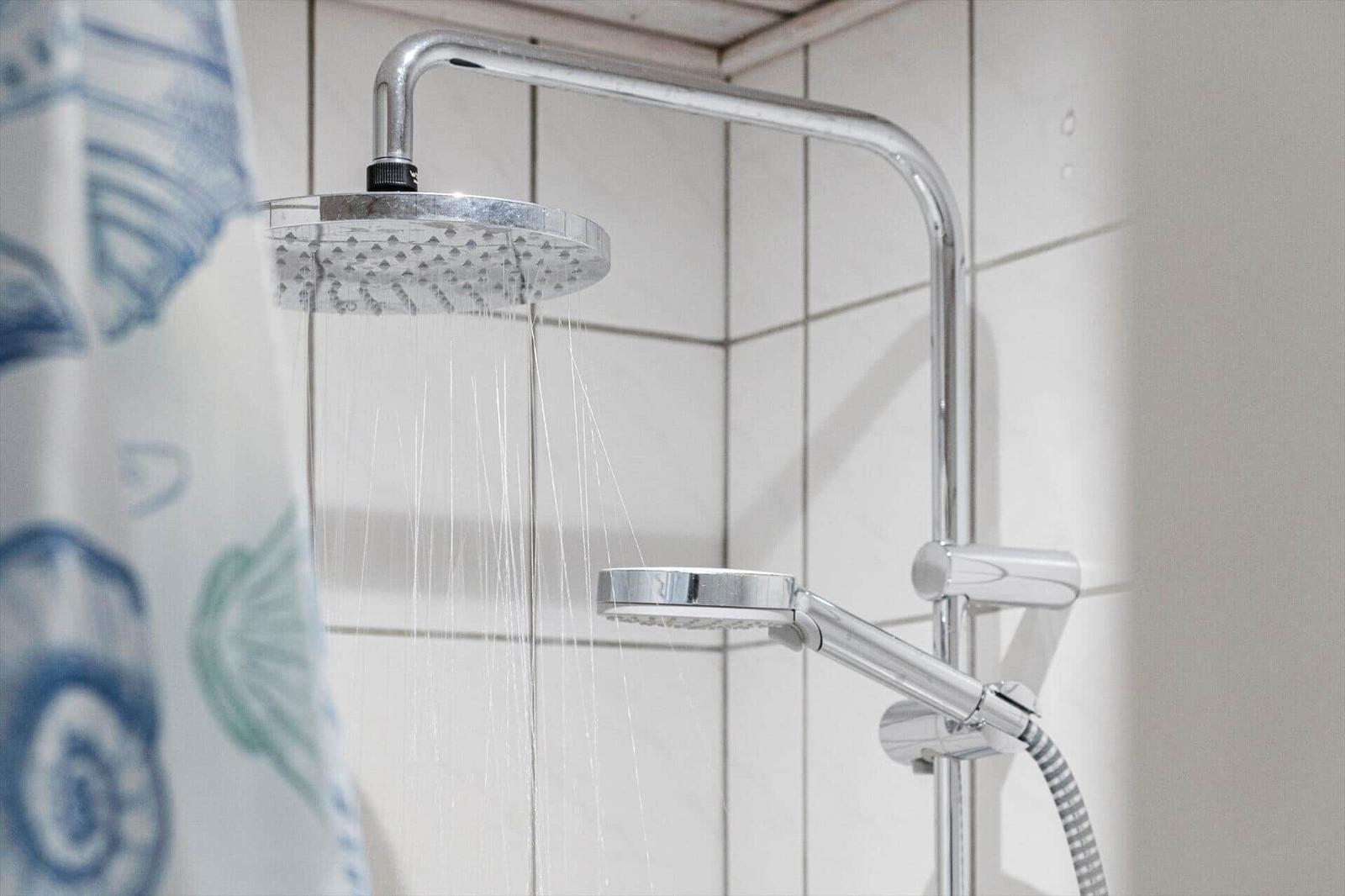 Duschkopf mit Regendusche und Handbrause an Wandhalterung.
