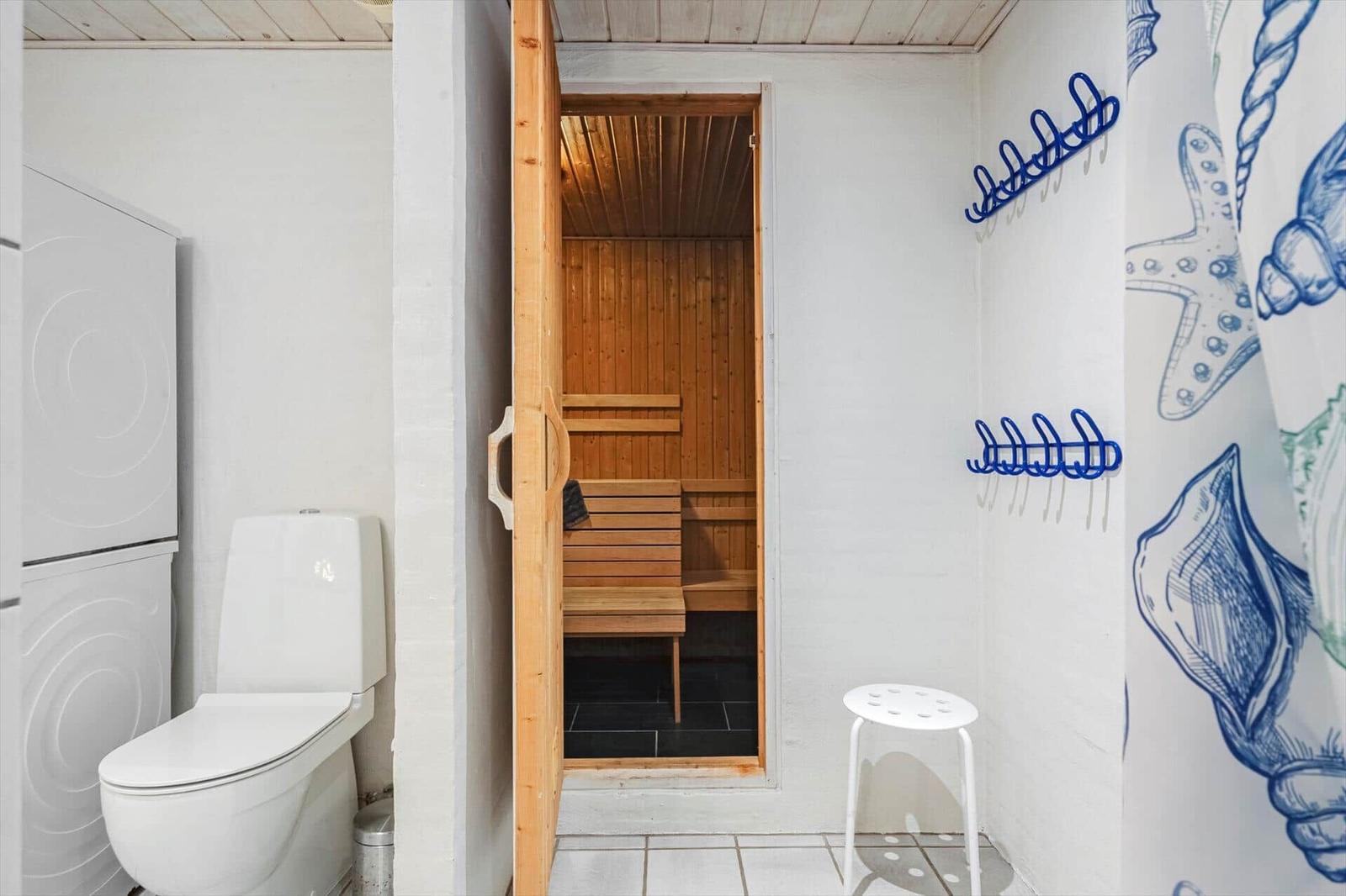Dusche mit Seestern-Badewannen-Teppich, Sauna mit Holzbank und Toilette.