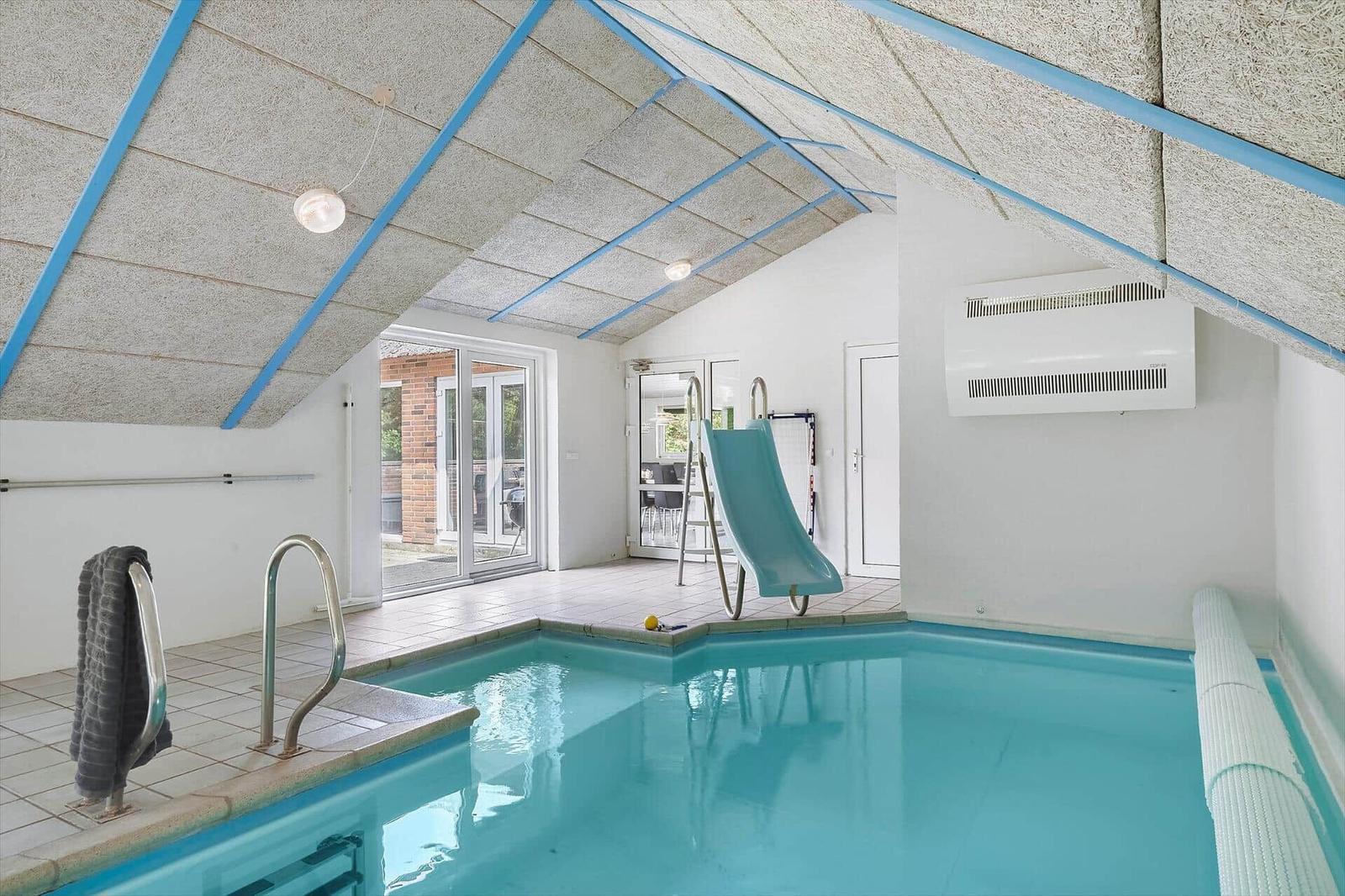 Innenpool mit Rutsche und Glasfront zum Garten.