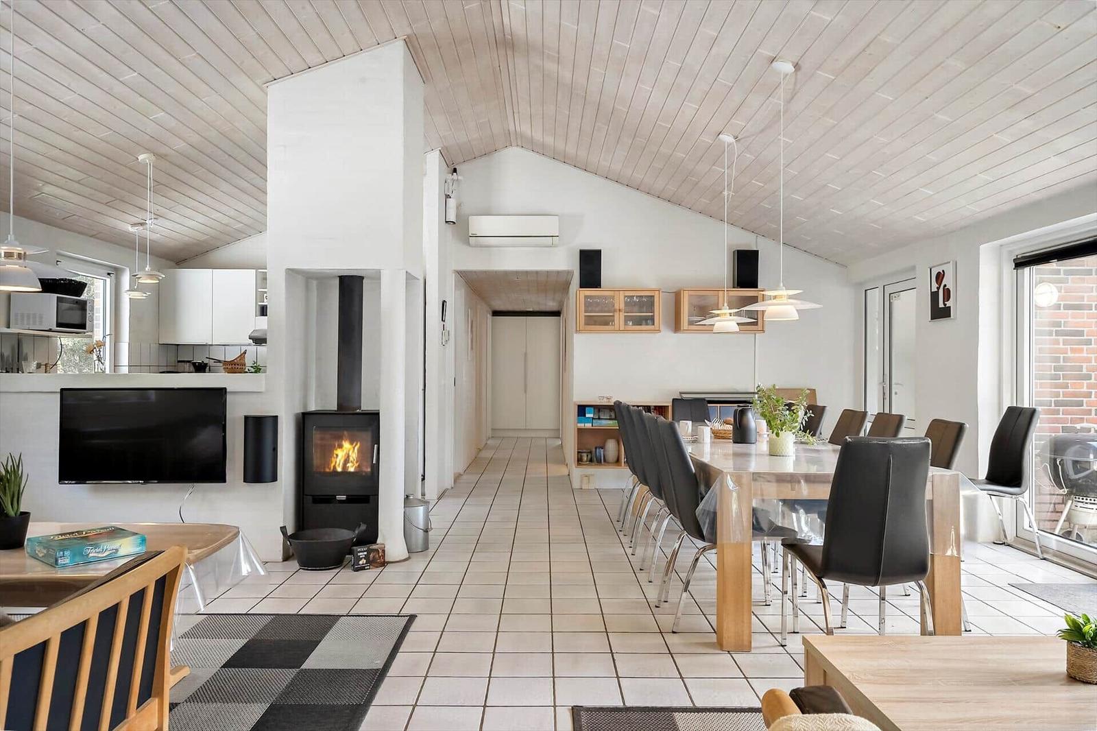 Großer Raum mit Essbereich, Kamin und Küche unter Holzdecke.