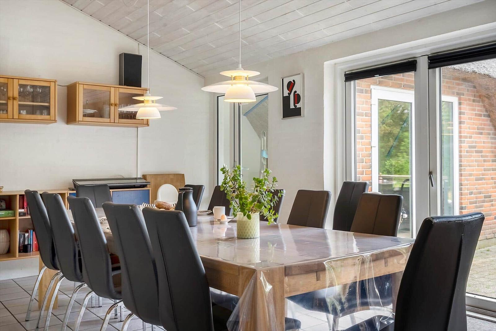 Esszimmer mit Holztisch, schwarzen Stühlen und Glasfront zur Terrasse.