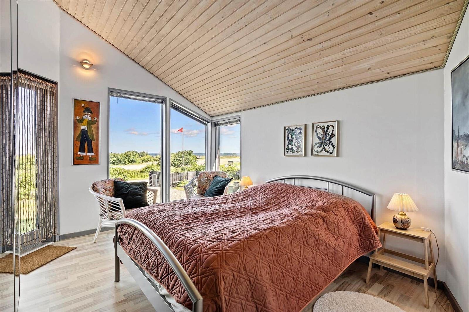Bedroom with bed, windows, and wooden ceiling. View of the landscape.