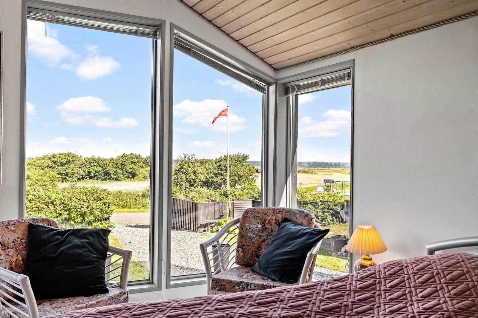 Room with view of garden and flag. Furniture and bed are visible.