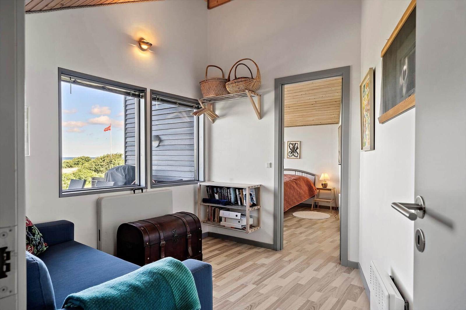 Living area with sea view, bedroom with bed and lamp visible.
