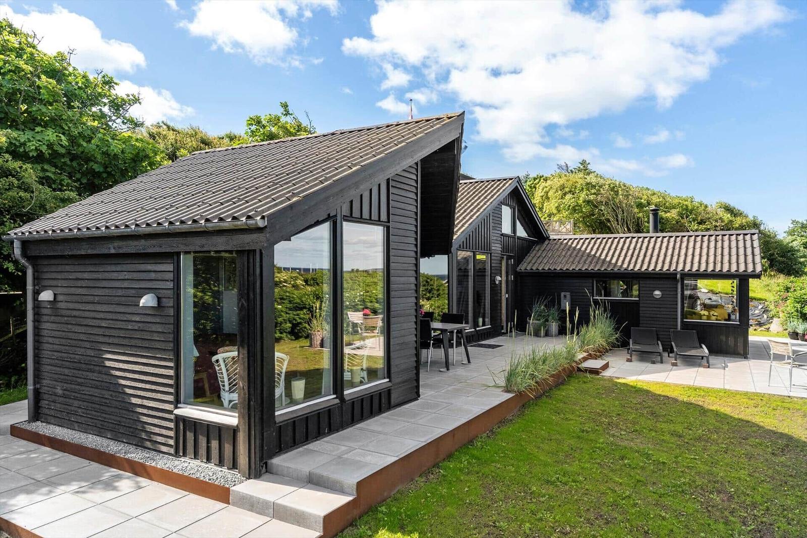 Modern wooden cabin with large terrace area and garden.