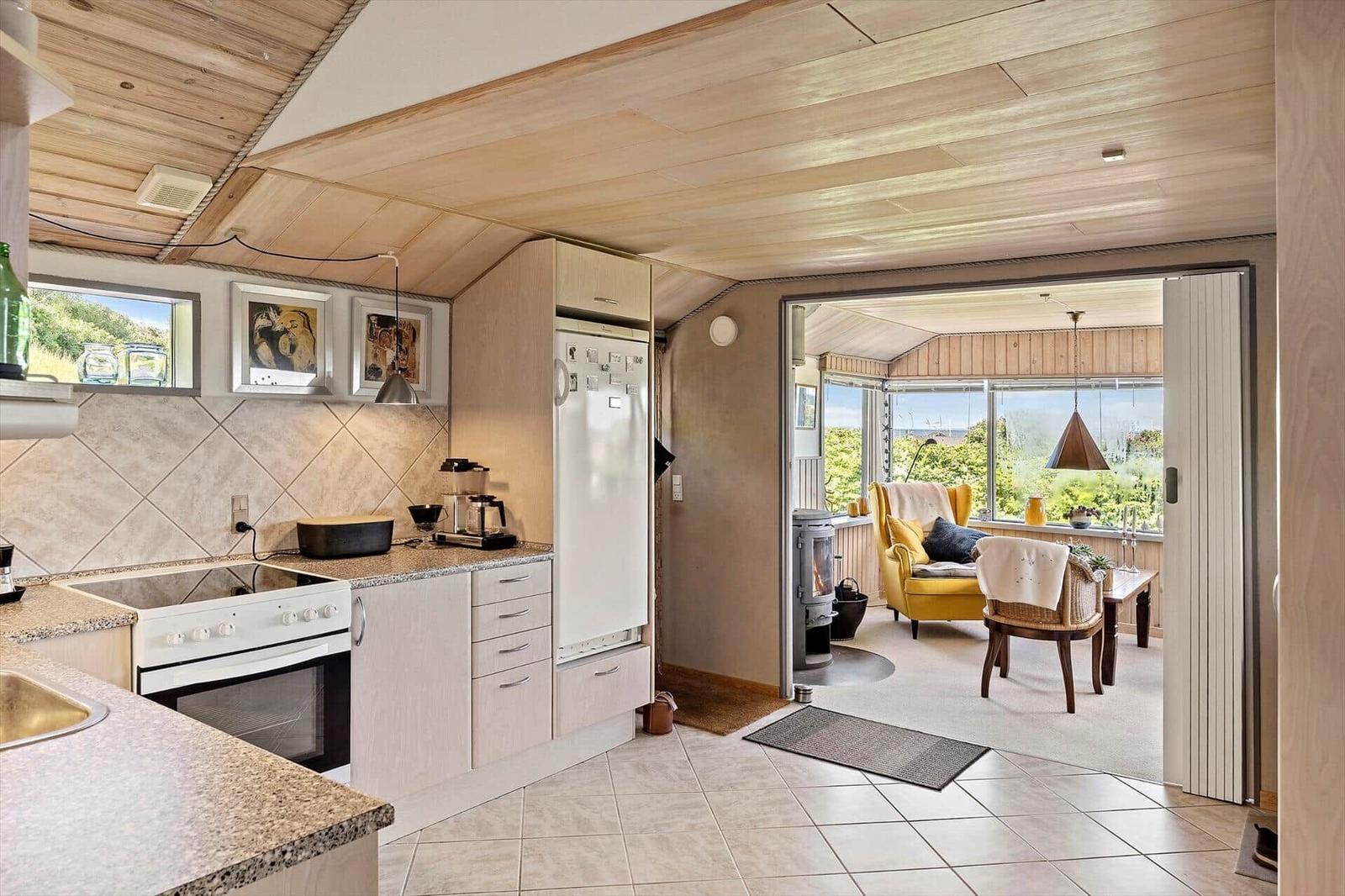 Kitchen with view of living area featuring yellow seating and wooden ceiling.
