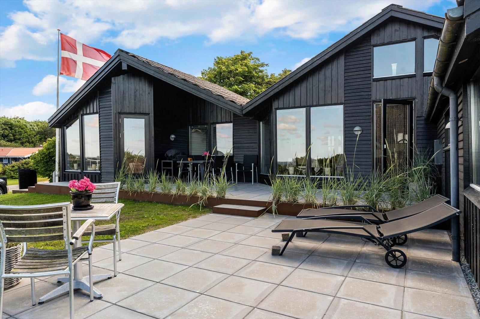 Modern villa with terrace, sun loungers, and Danish flag.