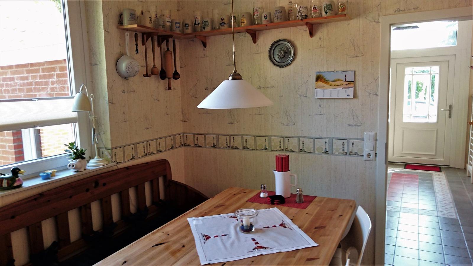 Esszimmer mit Holztisch, Bänken und Wandregalen mit Küchenutensilien.