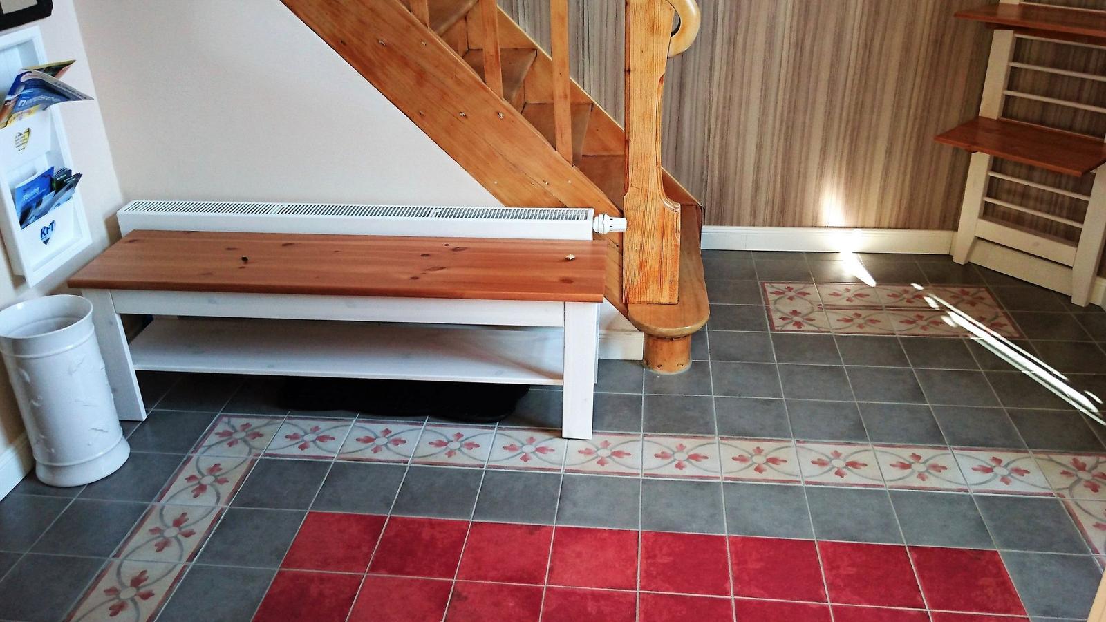 Holztreppe mit Sitzbank, gefliestes Boden mit Muster und Heizkörper.