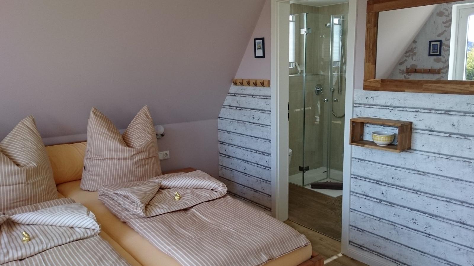 Zimmer mit Doppelbett, Dusche und Spiegel an der Wand