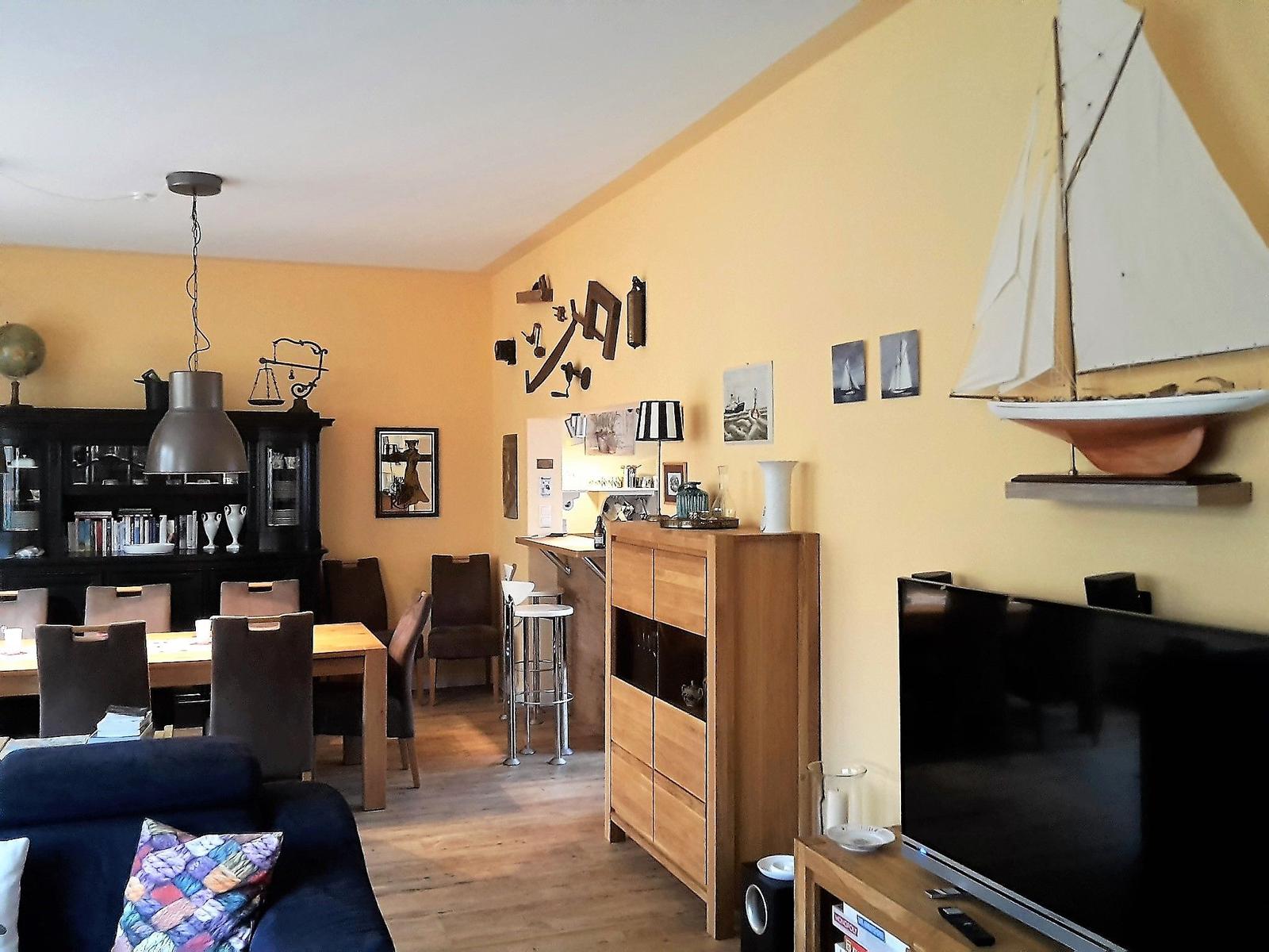 Wohn- und Essbereich mit Holzmöbeln, Wanddekoration und Fernseher.