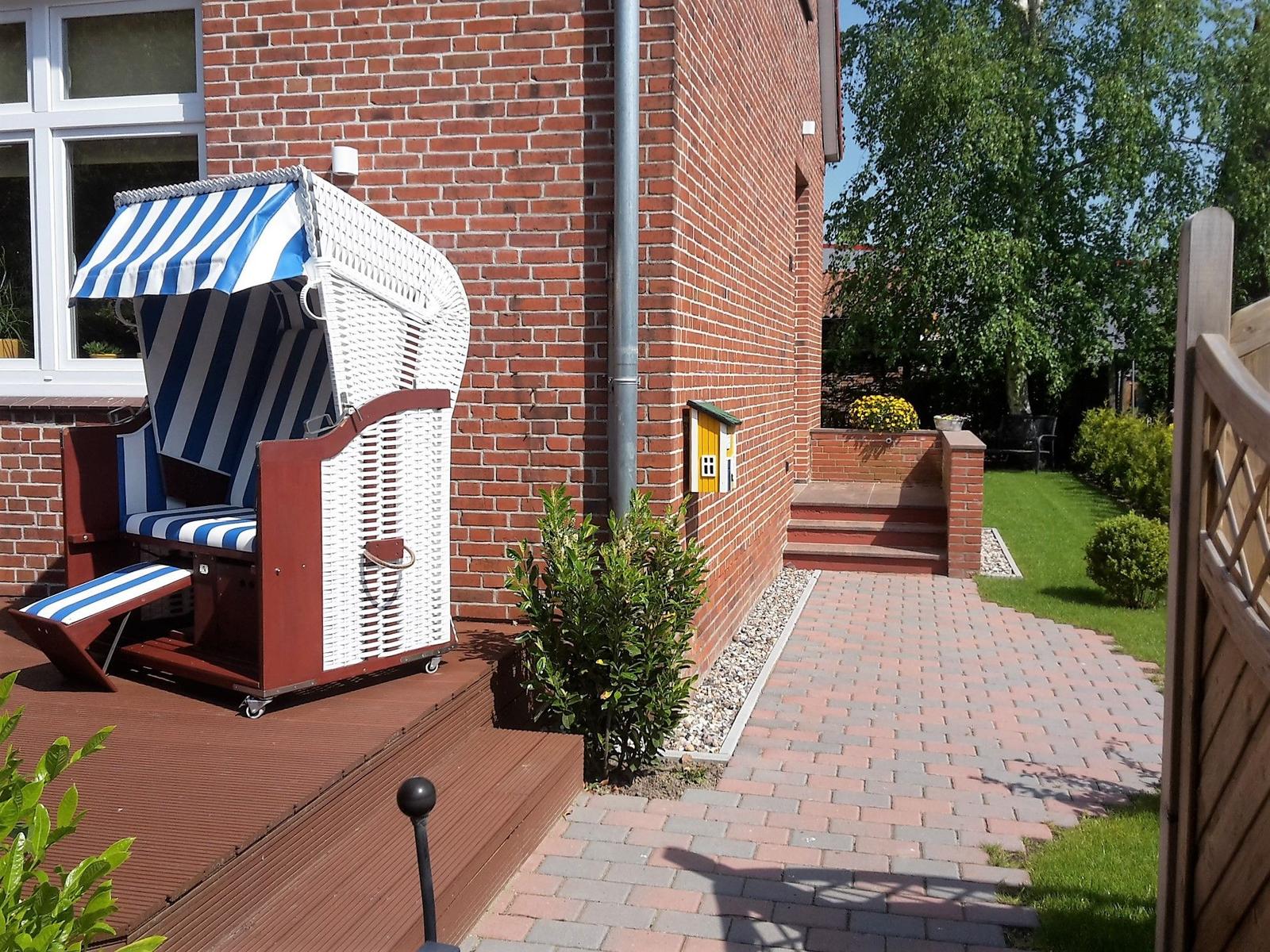 Haus mit Strandkorb, gepflastertem Weg und Garten.