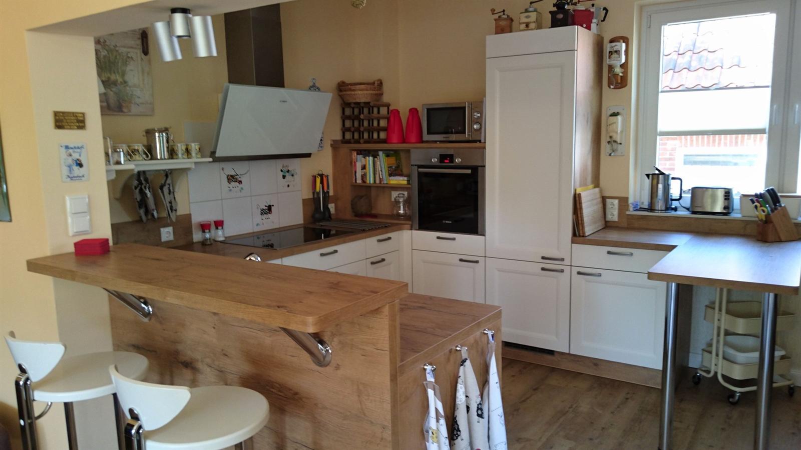 Küche mit Holzoberflächen, weißen Schränken und integriertem Backofen.