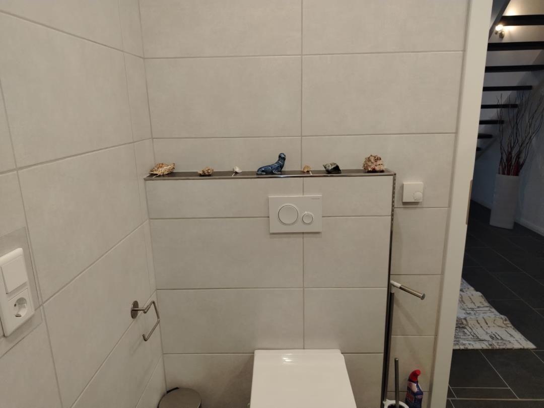 Toilette mit Wandhalter und Schale mit Muscheln und kleinen Figuren.