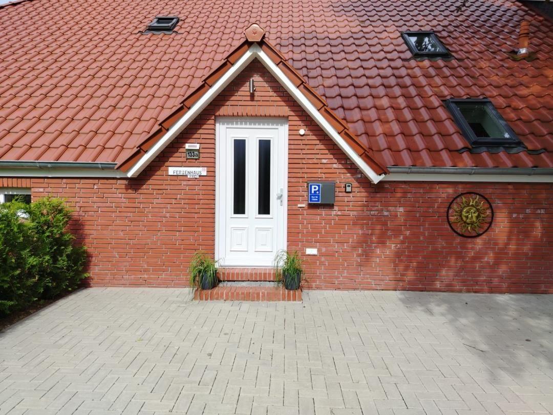 Rotes Ziegeldach, weiße Tür, gepflastertes Vorfeld, Sonnenmotiv an der Wand.