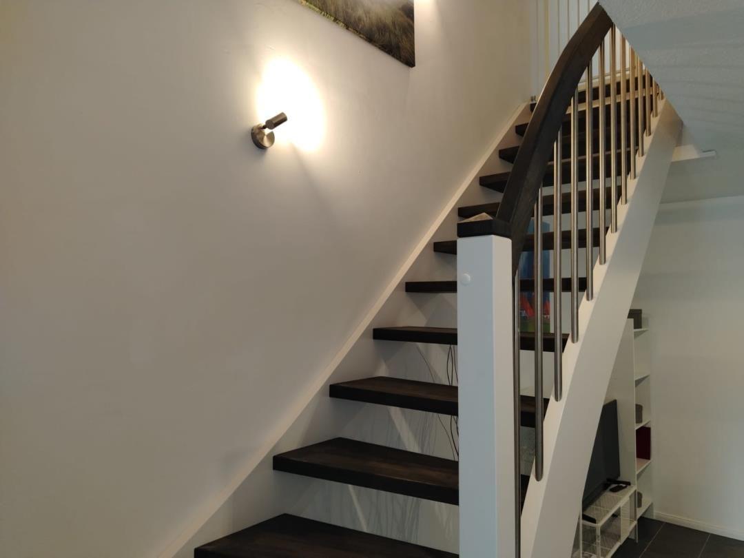 Treppe mit dunklen Stufen und weißem Geländer führt nach oben.