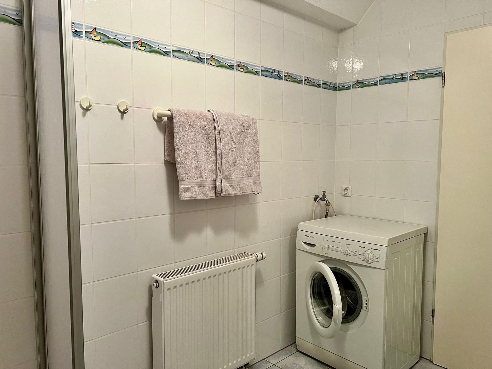 Waschmaschine in Badezimmer mit Handtuch und Heizkörper