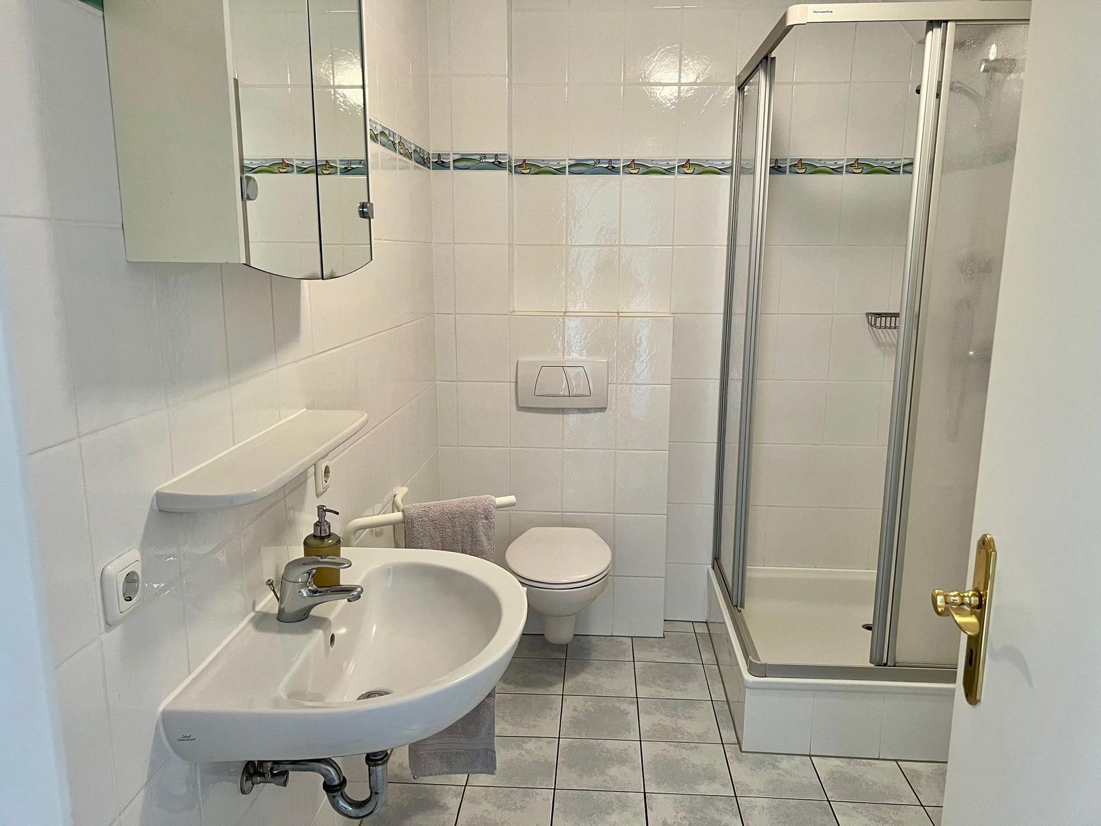 Badezimmer mit Dusche, Toilette und Waschbecken mit Spiegel.